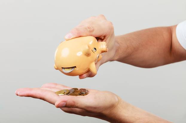 Male hands with coins and piggybank