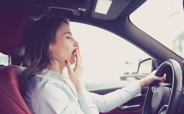 Sleepy woman driving her car after long hour trip isolated street background. Sleep deprivation and accident concept