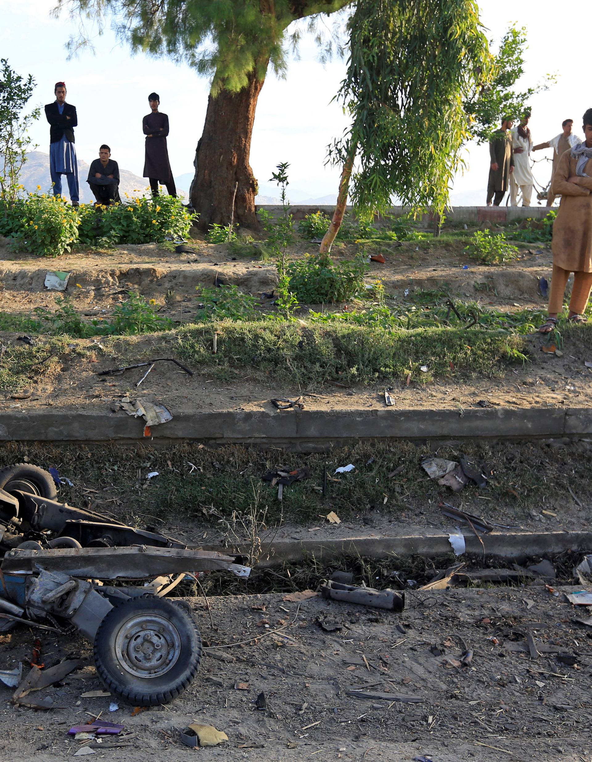 People look at a damaged auto rickshaw after blasts in Jalalabad city, Afghanistan