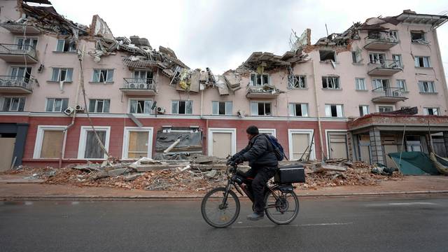 A local man rides a bicycle past the hotel Ukraina (Ukraine) destroyed by an airstrike in Chernihiv