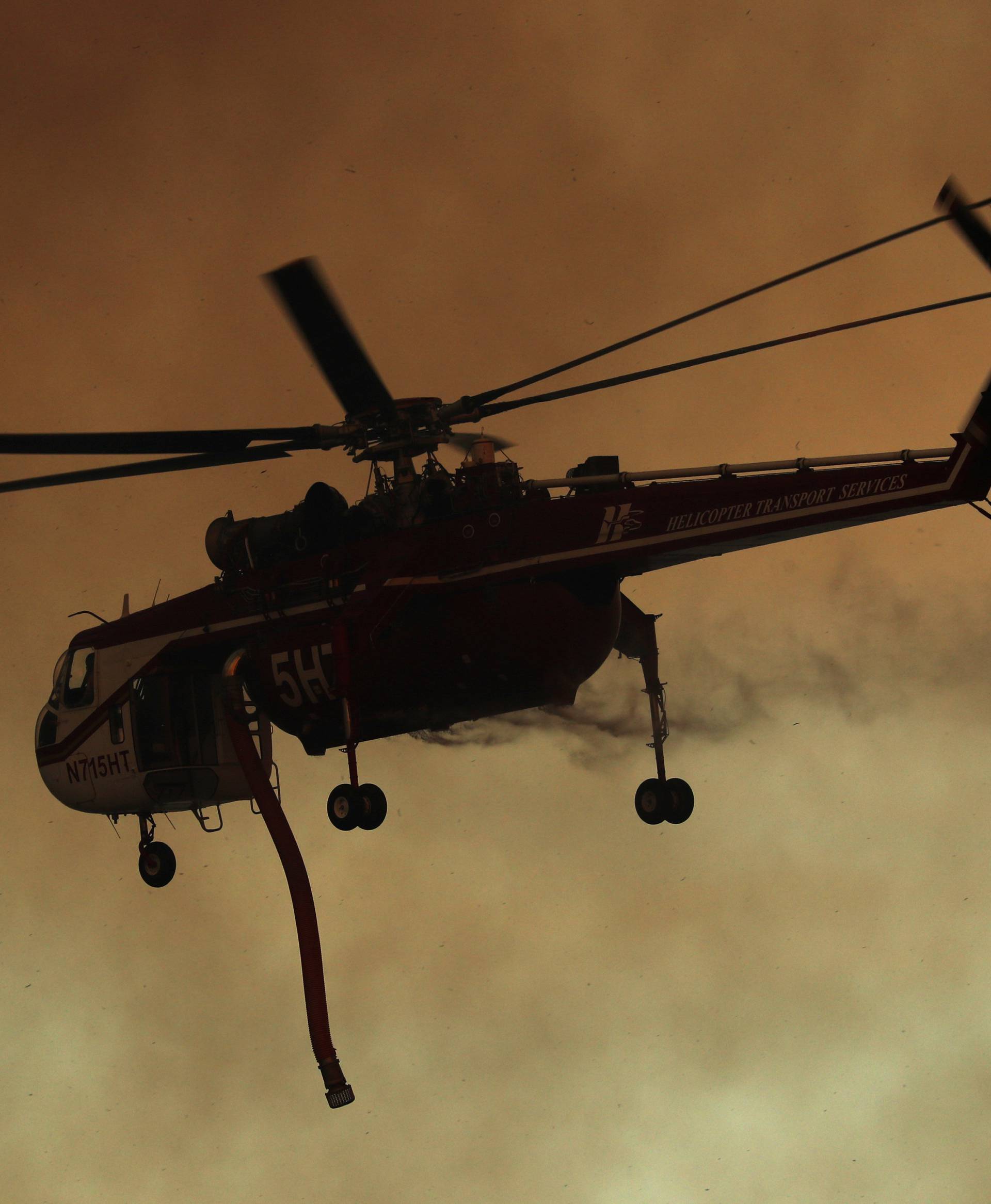 A firefighting helicopter flies in to make a water drop on a wind driven wildfire in Orange, California