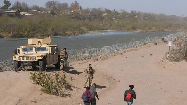 A group of migrants from Venezuela walk along the banks of the Rio Grande