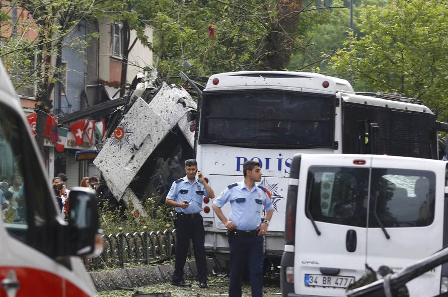 A policeman uses his phone near a Turkish police bus which was targeted in a bomb attack in a central Istanbul district