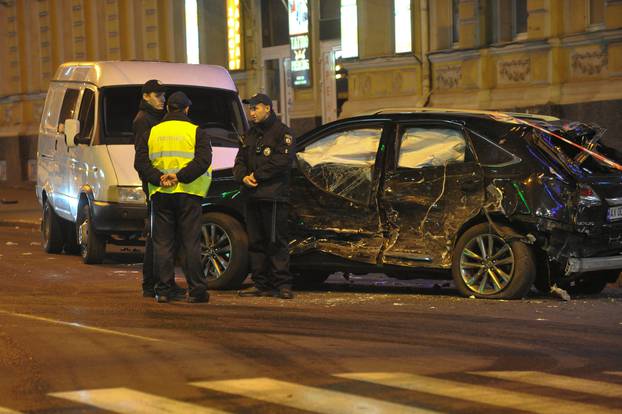 Policemen stand next to a damaged sport utility vehicle (SUV) at the accident scene after a car drove into pedestrians following a vehicle collision in central Kharkiv