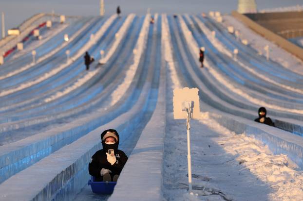 A person slides down an ice slide at the annual Ice and Snow Festival in Harbin