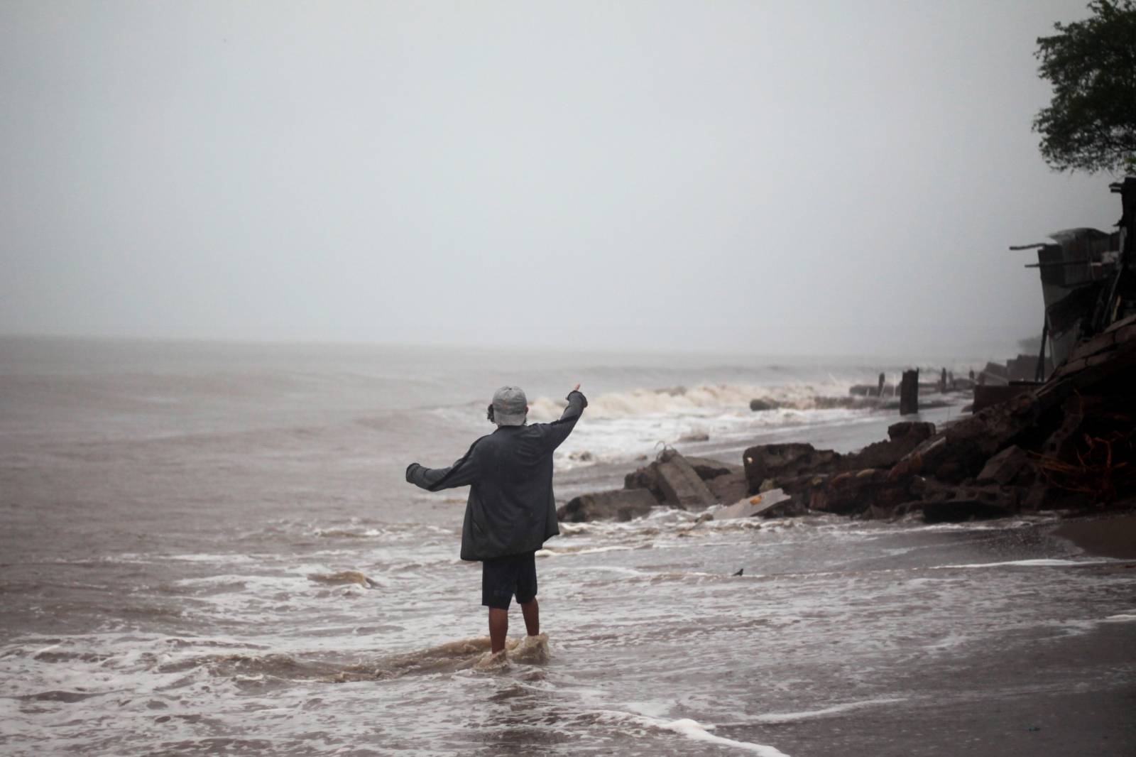 Man gestures as he stands on a beach after the passing of Storm Iota, in Cedeno
