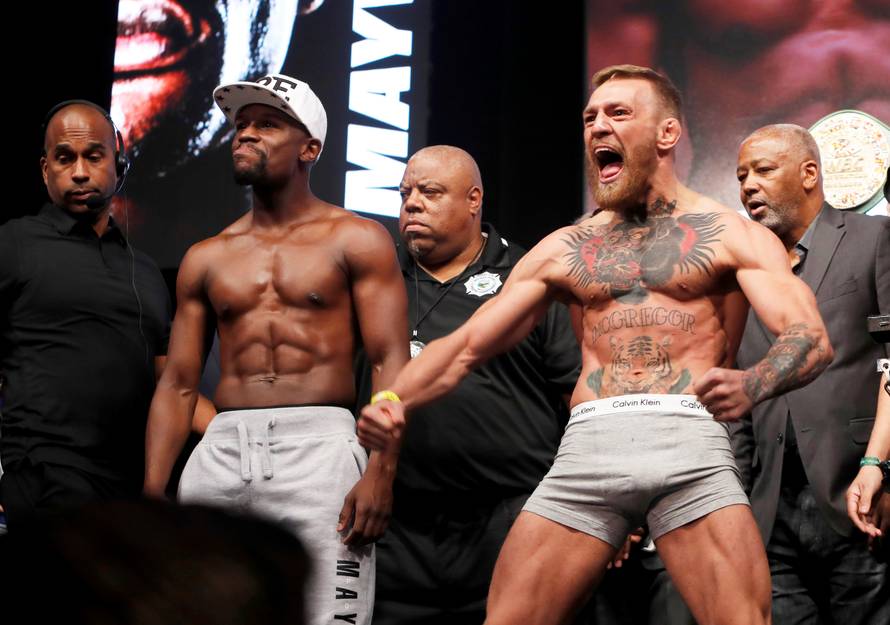 Undefeated boxer Floyd Mayweather Jr. (L) of the U.S. and UFC lightweight champion Conor McGregor of Ireland pose during their official weigh-in at T-Mobile Arena in Las Vegas