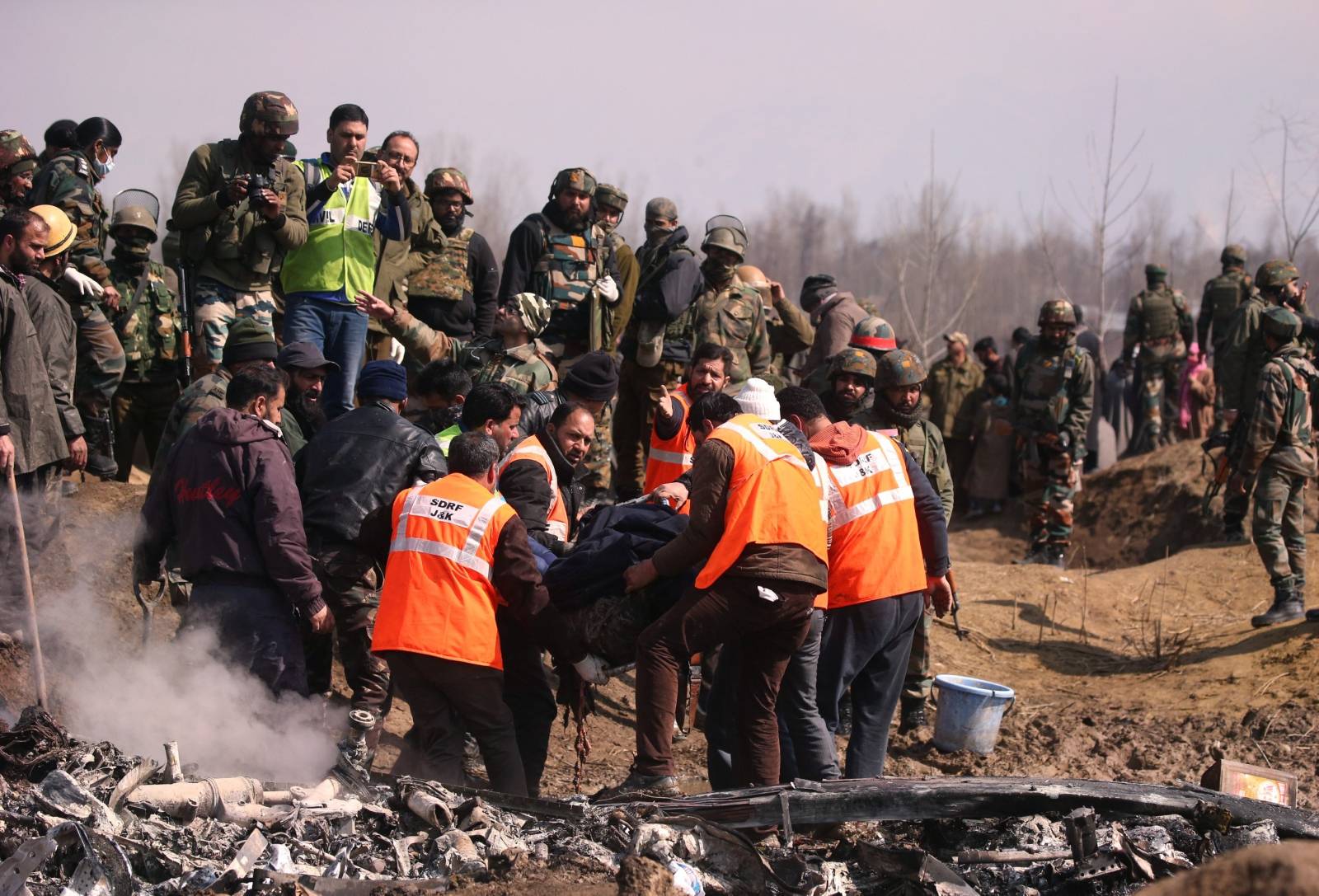 Members of State Disaster Response Force remove a body from the wreckage of Indian Air Force's helicopter after it crashed in Budgam district