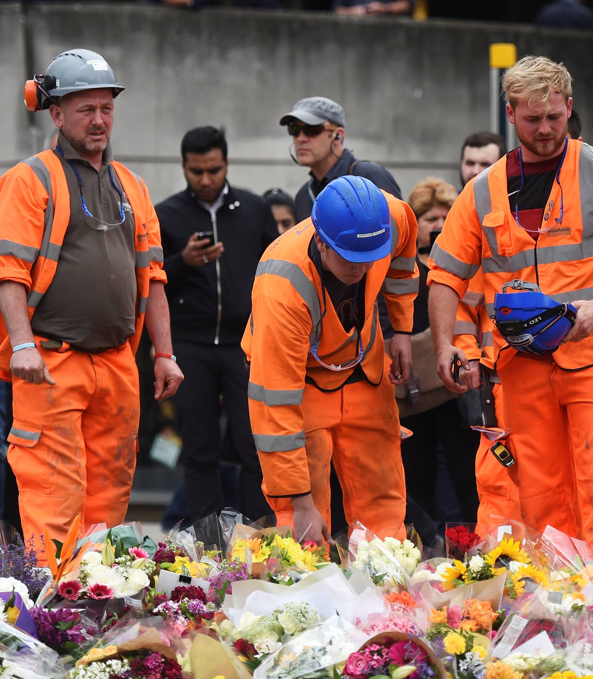 A group of construction workers react as they leave flowers on the south side of London Bridge near Borough Market after an attack left 7 people dead and dozens of injured in London