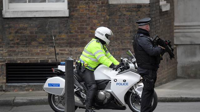 An armed police officer and police motorcycle outrider stand on duty in Downing Street, London