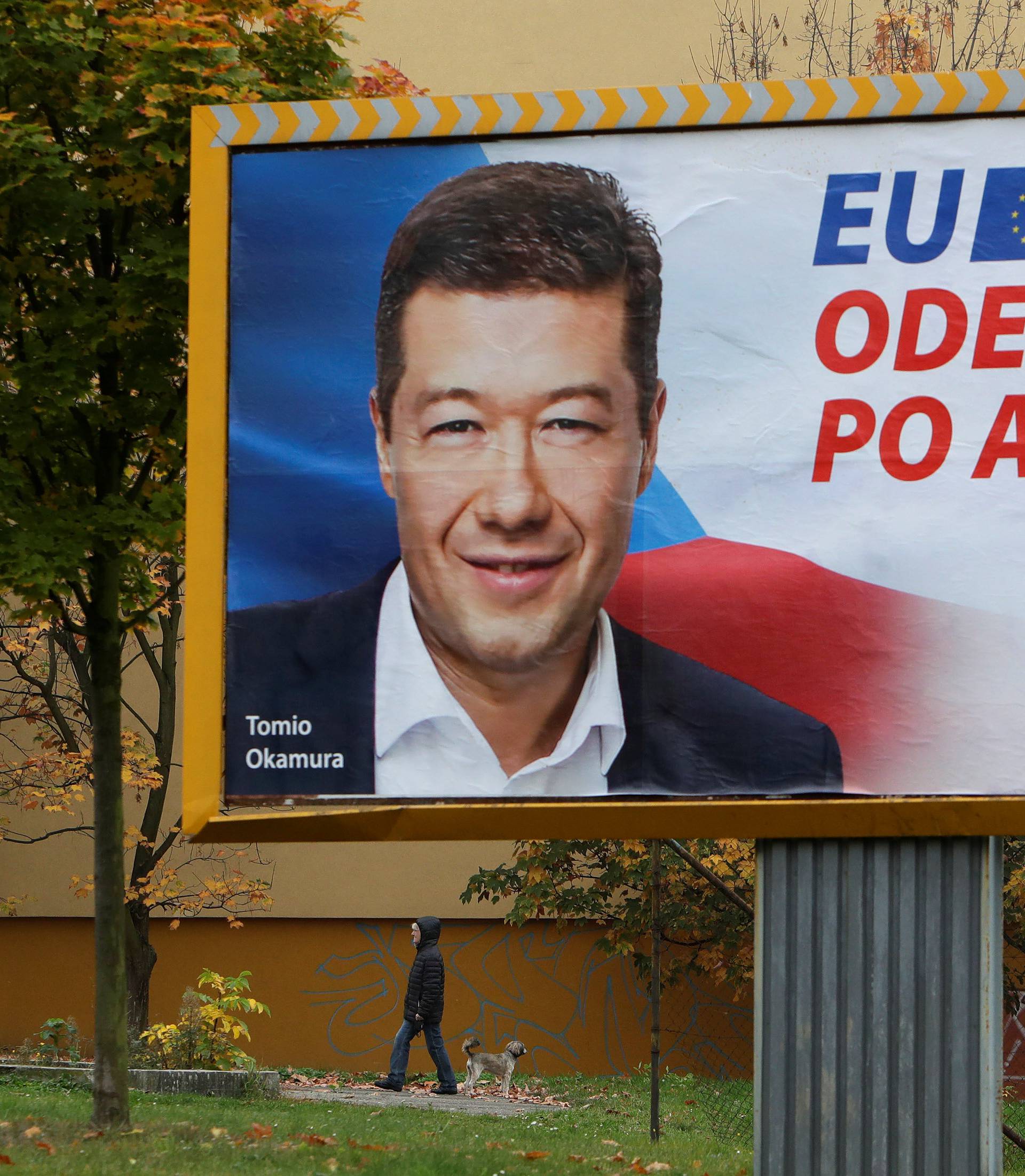 A woman walks her dog under an election campaign poster of the leader of Freedom and Direct Democracy (SPD) party Tomio Okamura in Prague