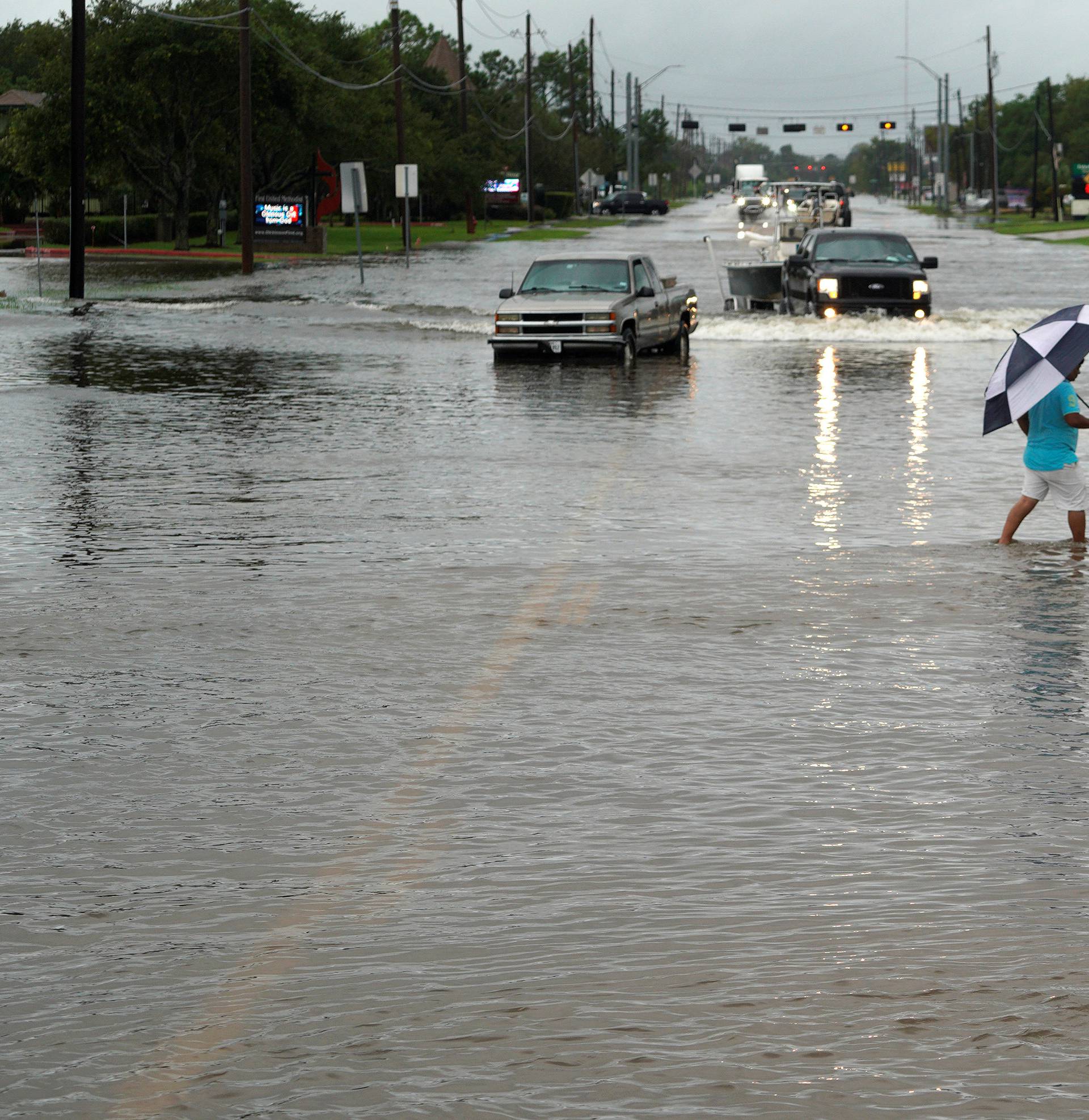 A woman walks across the main street through the Hurricane Harvey floodwaters in Dickinson