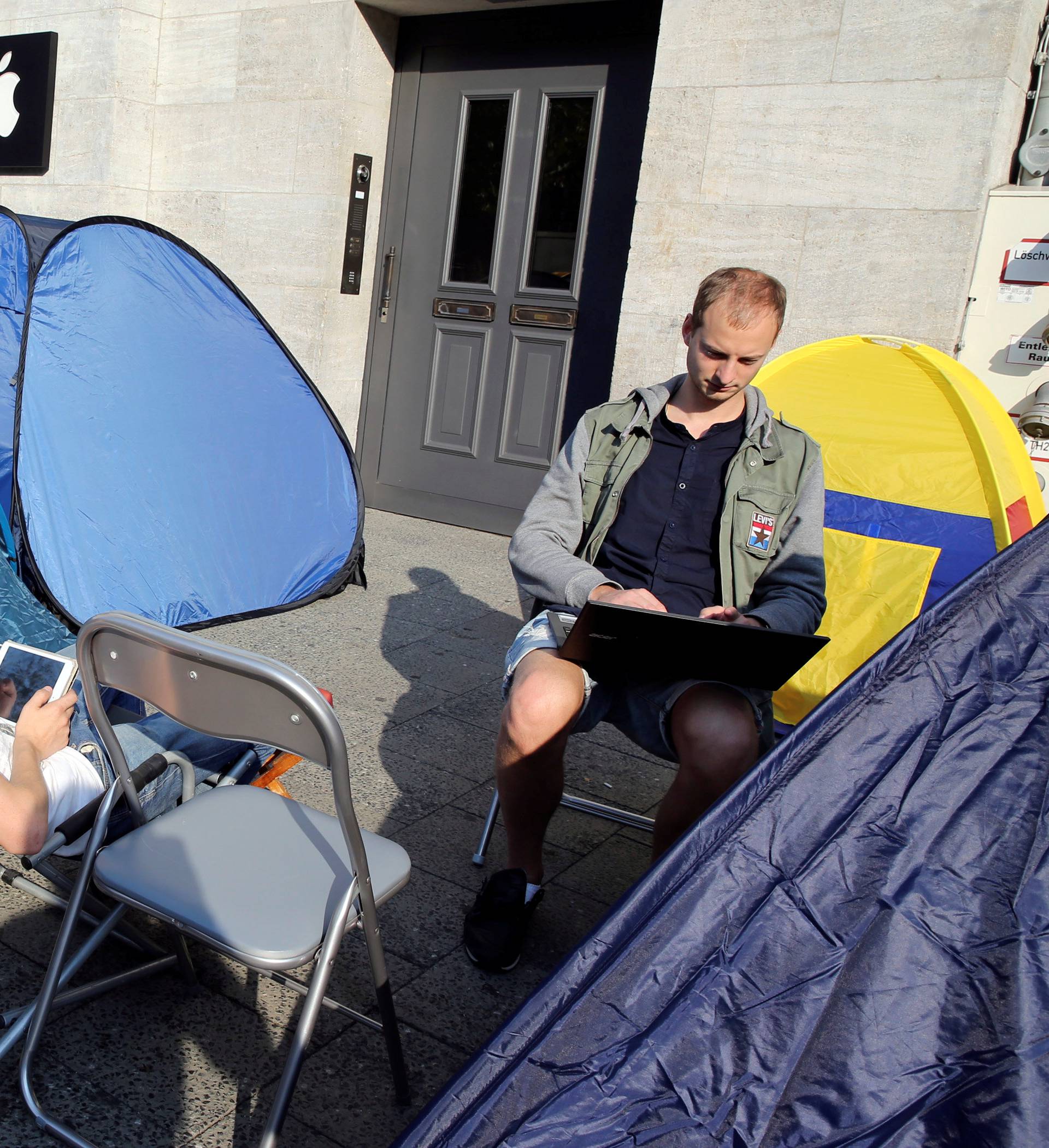 Customers from Belarus wait beside their tents outside an Apple store to buy the newly released Apple iPhone 7 in Berlin