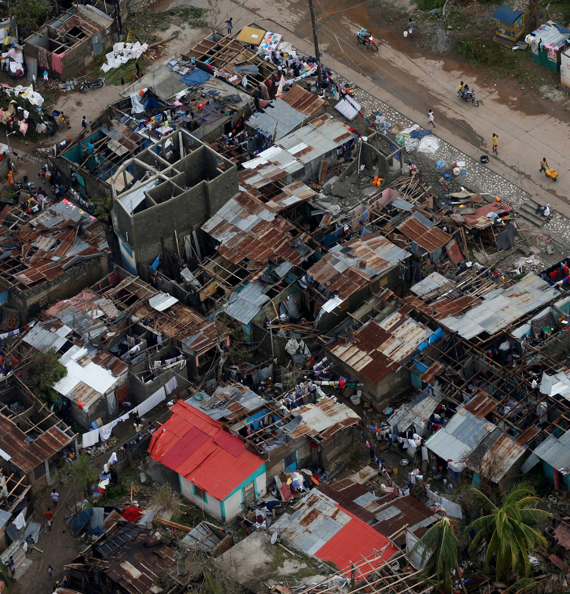 People walk down the street next to destroyed houses after Hurricane Matthew passes Jeremie, Haiti