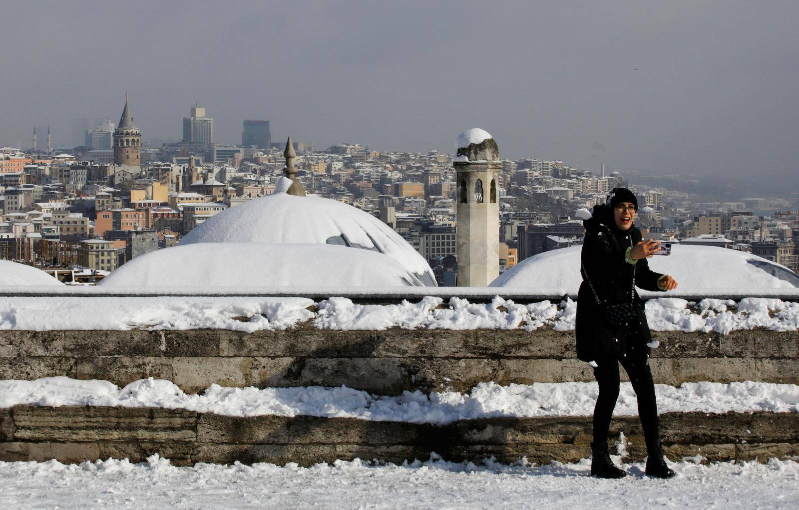 A woman enjoys a snowy day at the garden of Suleymaniye Mosque in Istanbul