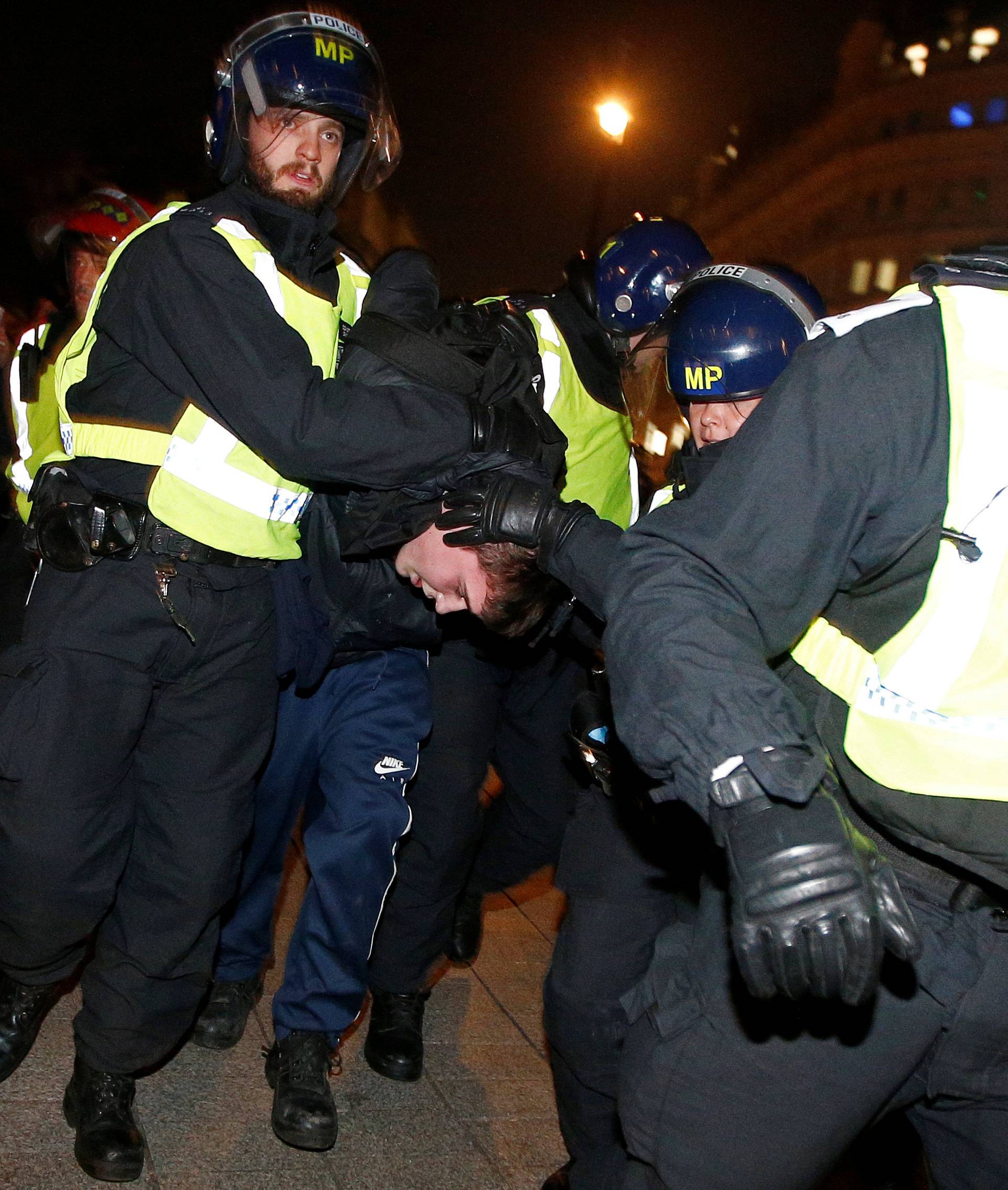 Police officers apprehend a protester during the "Million Mask March" in London