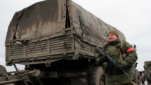 A serviceman of pro-Russian militia walks next to a military convoy in the Luhansk region