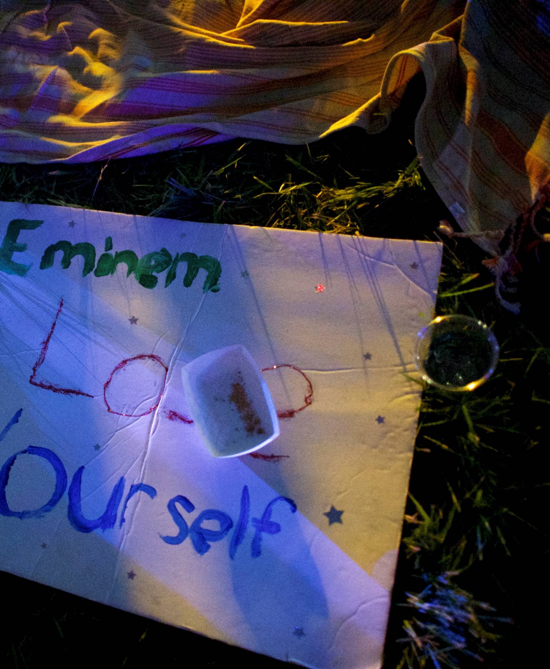 A sign stating "Eminem Lose Yourself" lies on the grass as he performs on the third day of the Firefly Music Festival in Dover, Delaware