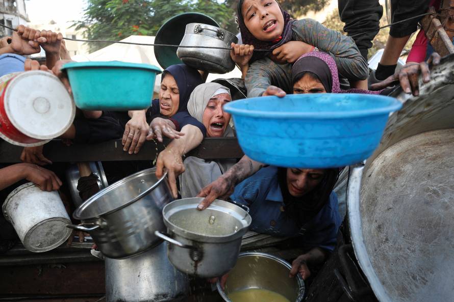 Palestinians wait to receive food from a charity kitchen, amid a hunger crisis, in Gaza City
