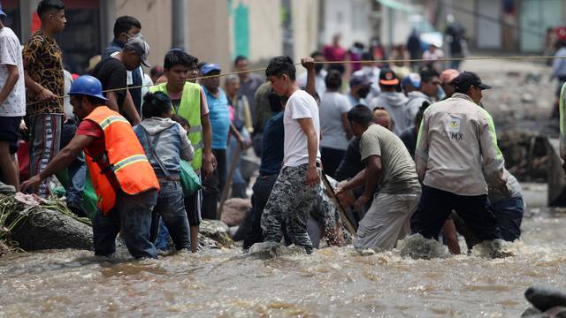 People clean up debris of the damage caused by heavy rainfall in the municipality of Ecatepec