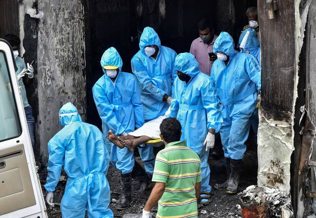 Rescue workers carry the body of a patient suffering from coronavirus disease, who died after a fire broke out in a hotel that was being used as a COVID-19 facility, in Vijayawada