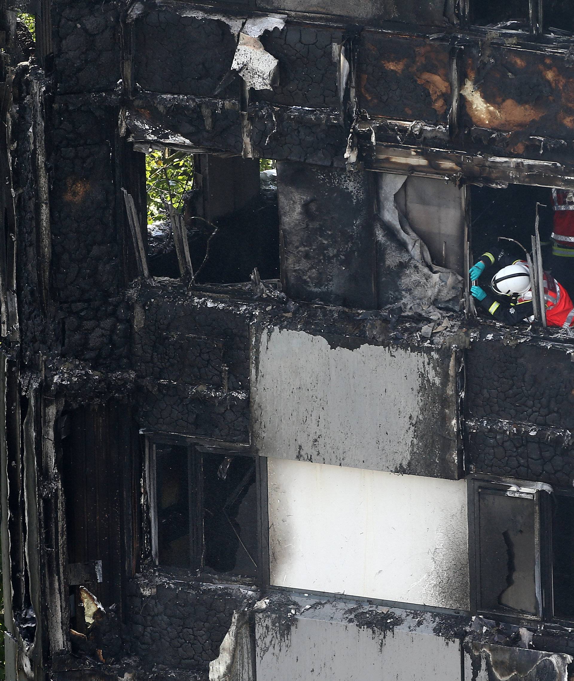 A firefighter examines material in a tower block severely damaged by a serious fire, in north Kensington, West London