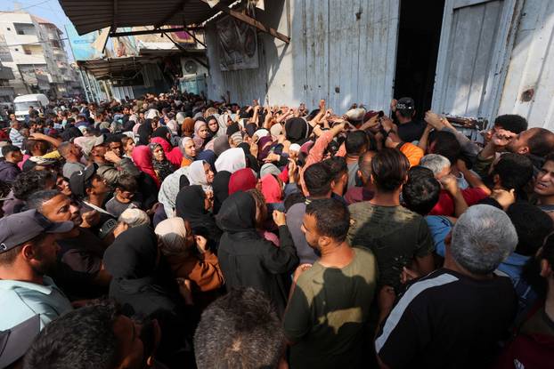 Palestinians gather as they wait to buy bread from a bakery, in Deir Al-Balah, central Gaza Strip
