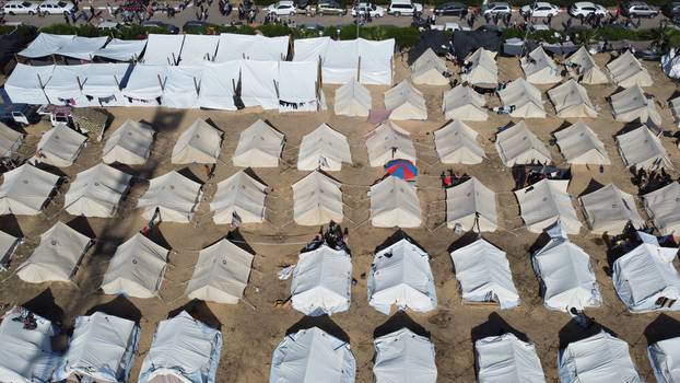 Palestinians, who fled their houses amid Israeli strikes, take shelter in a tent camp at a UN-run centre, in Khan Younis