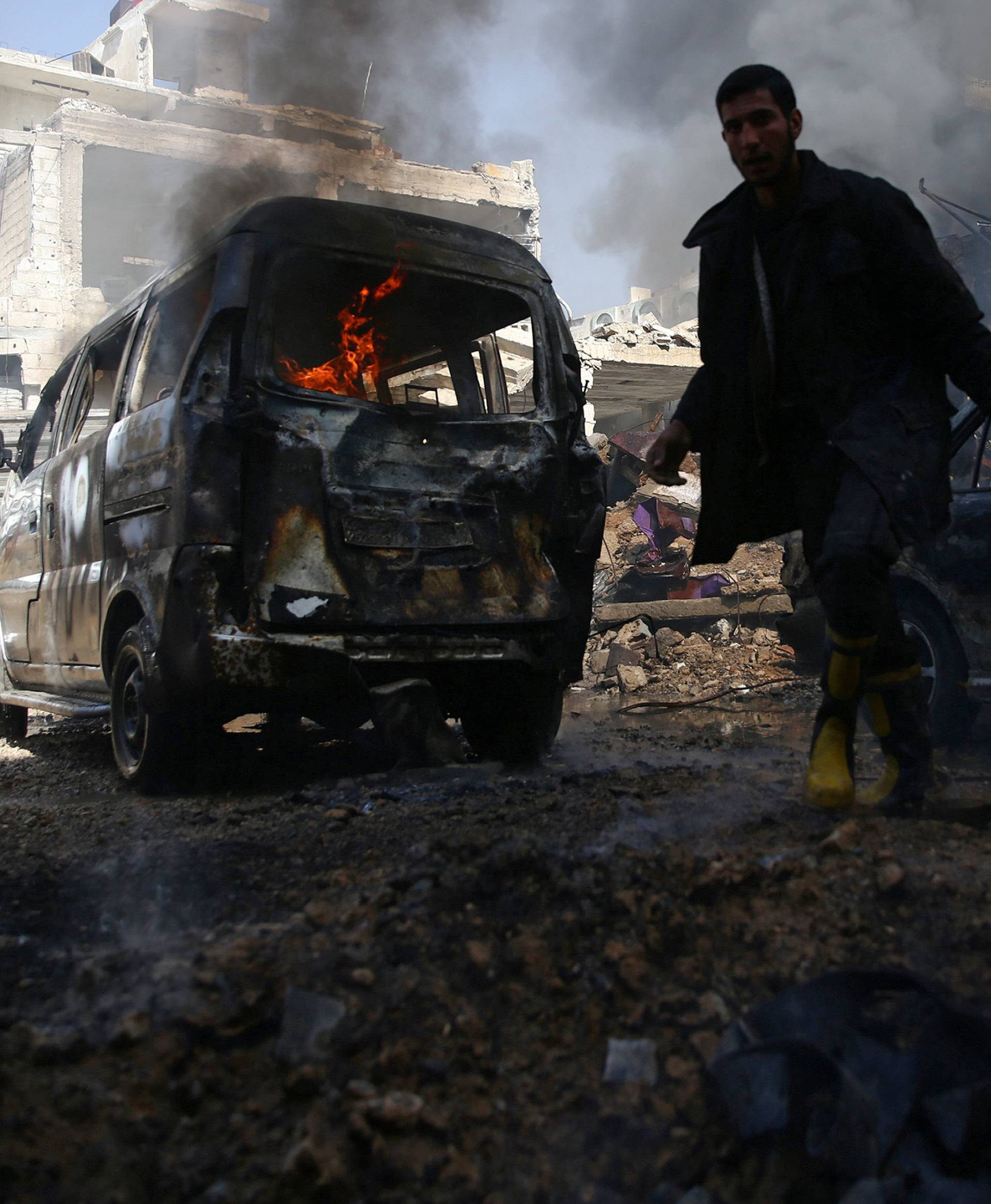 A civil defence member works amid burning vehicles at a site hit by airstrikes in the rebel held besieged Douma neighbourhood of Damascus
