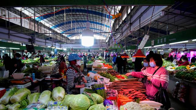 People wearing face masks buy vegetables at a wet market, following an outbreak of the coronavirus disease (COVID-19) in Wuhan