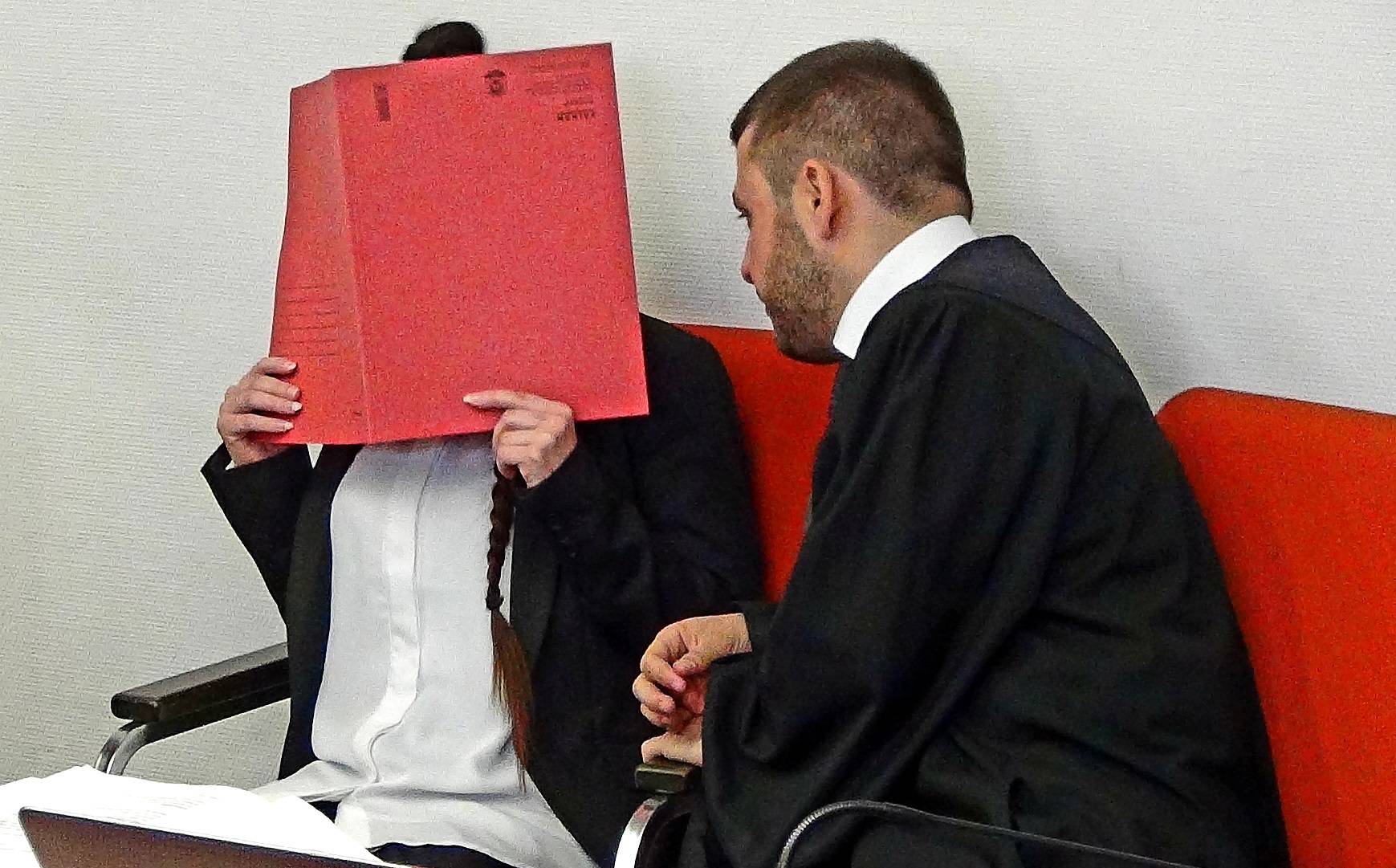 Defendant Jennifer W. covers her face as she waits for the start of the trial in Munich