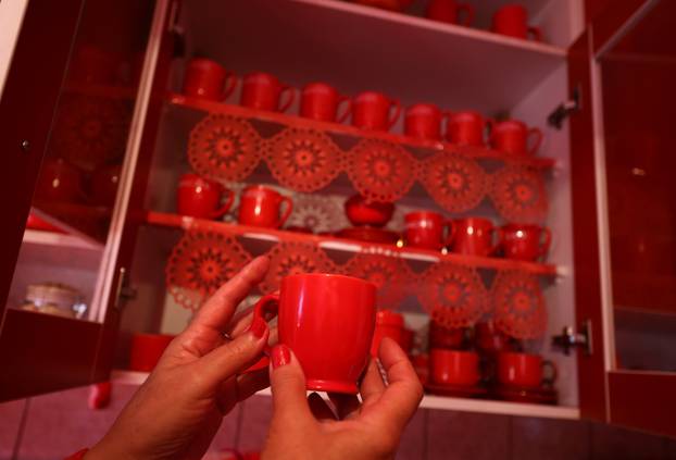 Zorica Rebernik, obsessed with the red color, holds a coffee cup in the kitchen inside her house in the village of Breze near Tuzla