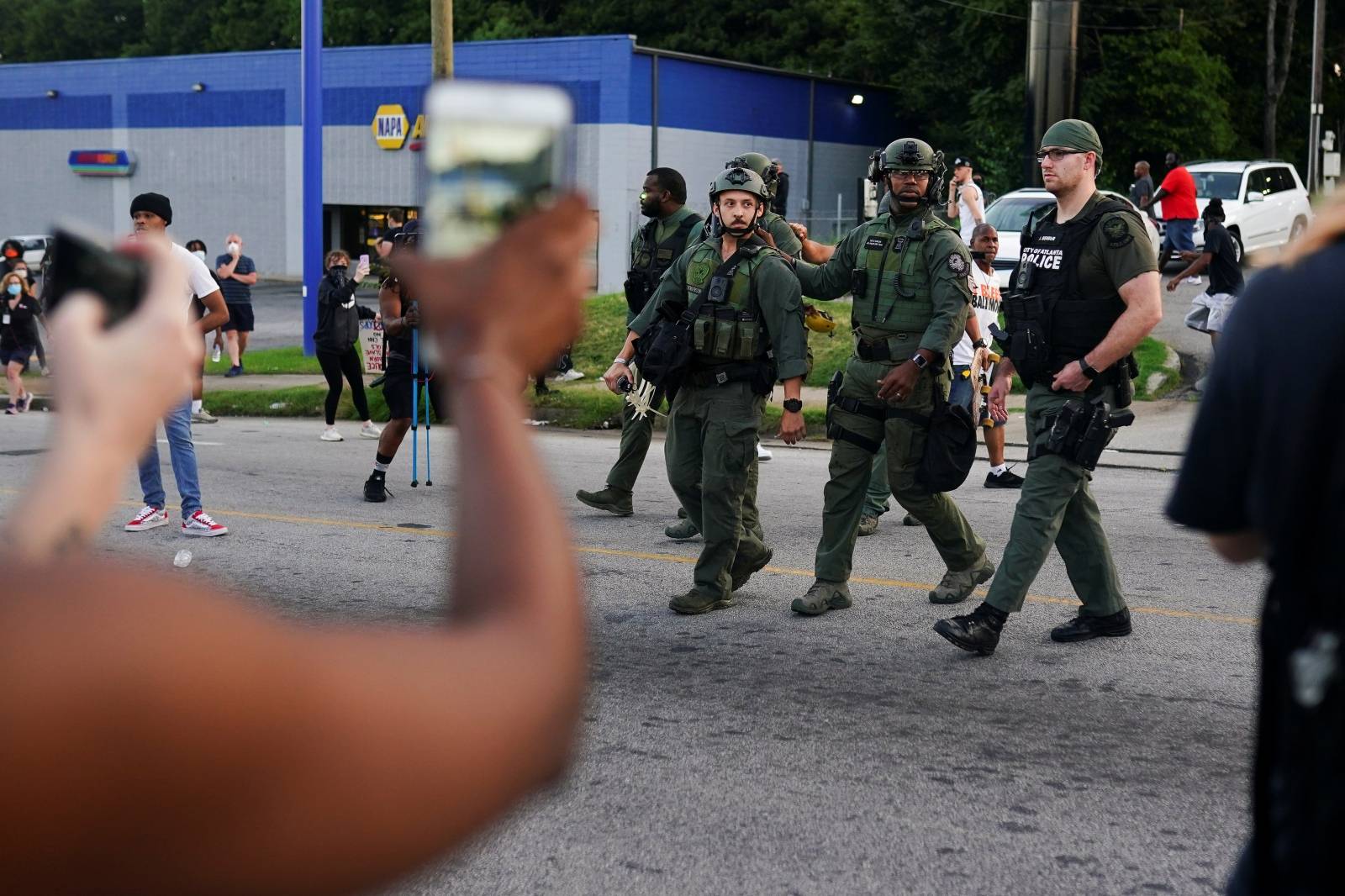 Protesters film police officers as they retreat during a rally against racial inequality and the police shooting death of Rayshard Brooks, in Atlanta