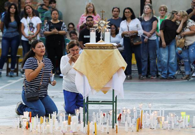 People take part in a candle vigil outside a church to pray for victims of earthquakes, in Valencia