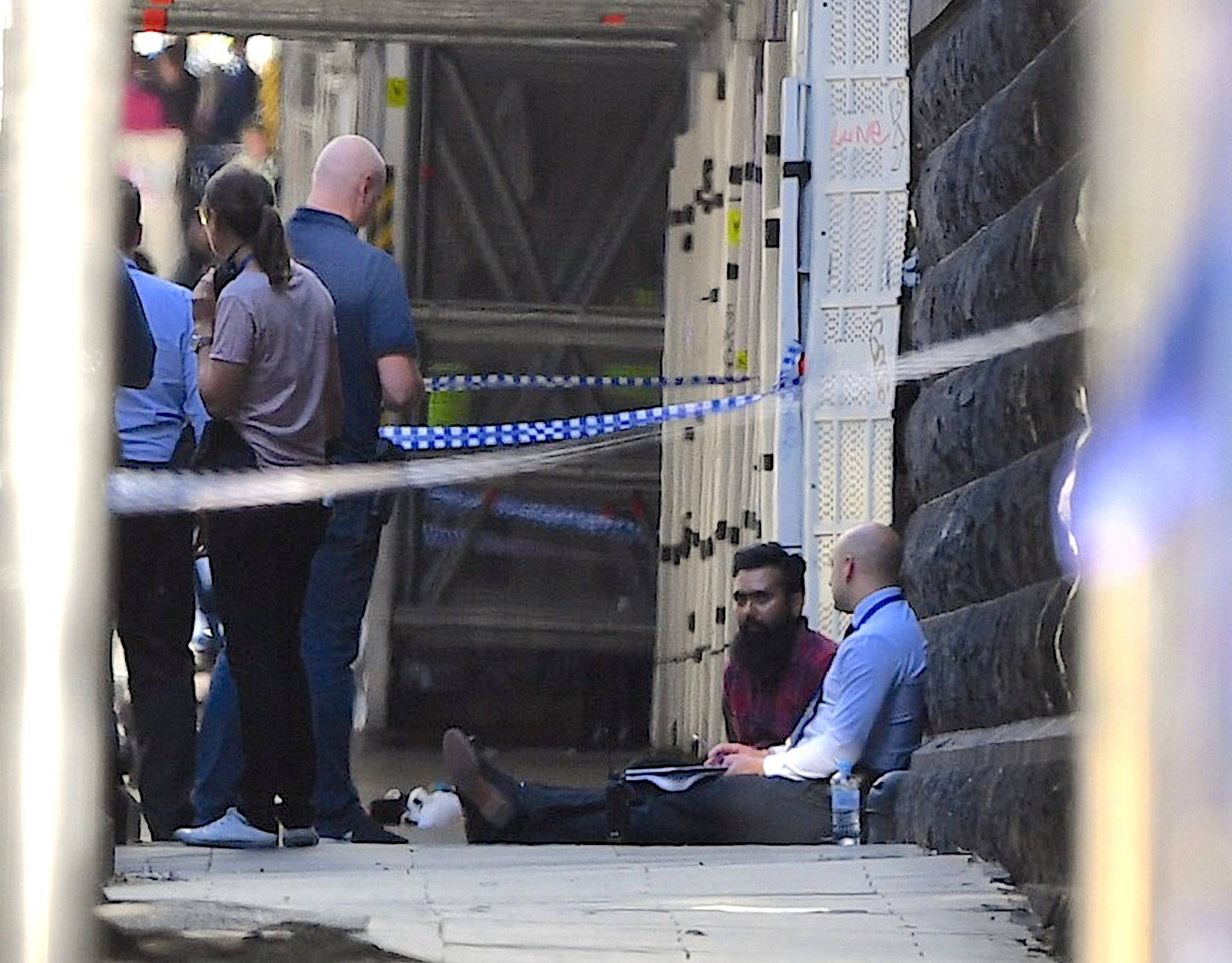 Man sits at the scene of an incident involving a vehicle ploughing into pedestrians at a crowded intersection near the Flinders Street train station in central Melbourne