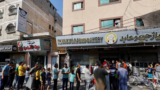Palestinians wait to buy bread outside a bakery in Khan Younis