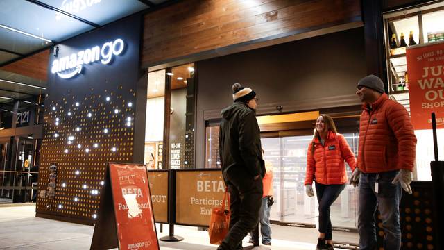 Amazon employees are pictured outside the Amazon Go brick-and-mortar grocery store without lines or checkout counters, in Seattle Washington