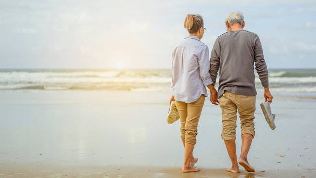 Senior,Couple,Walking,On,The,Beach,Holding,Hands,At,Sunrise,