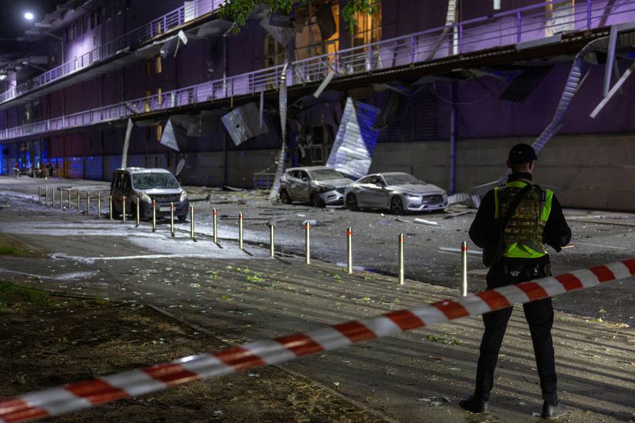 A policeman stands outside a shopping mall that was damaged during a Russian drone attack in Kyiv