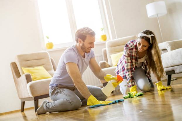 Shallow focus shot of a happy Caucasian couple cleaning the house together