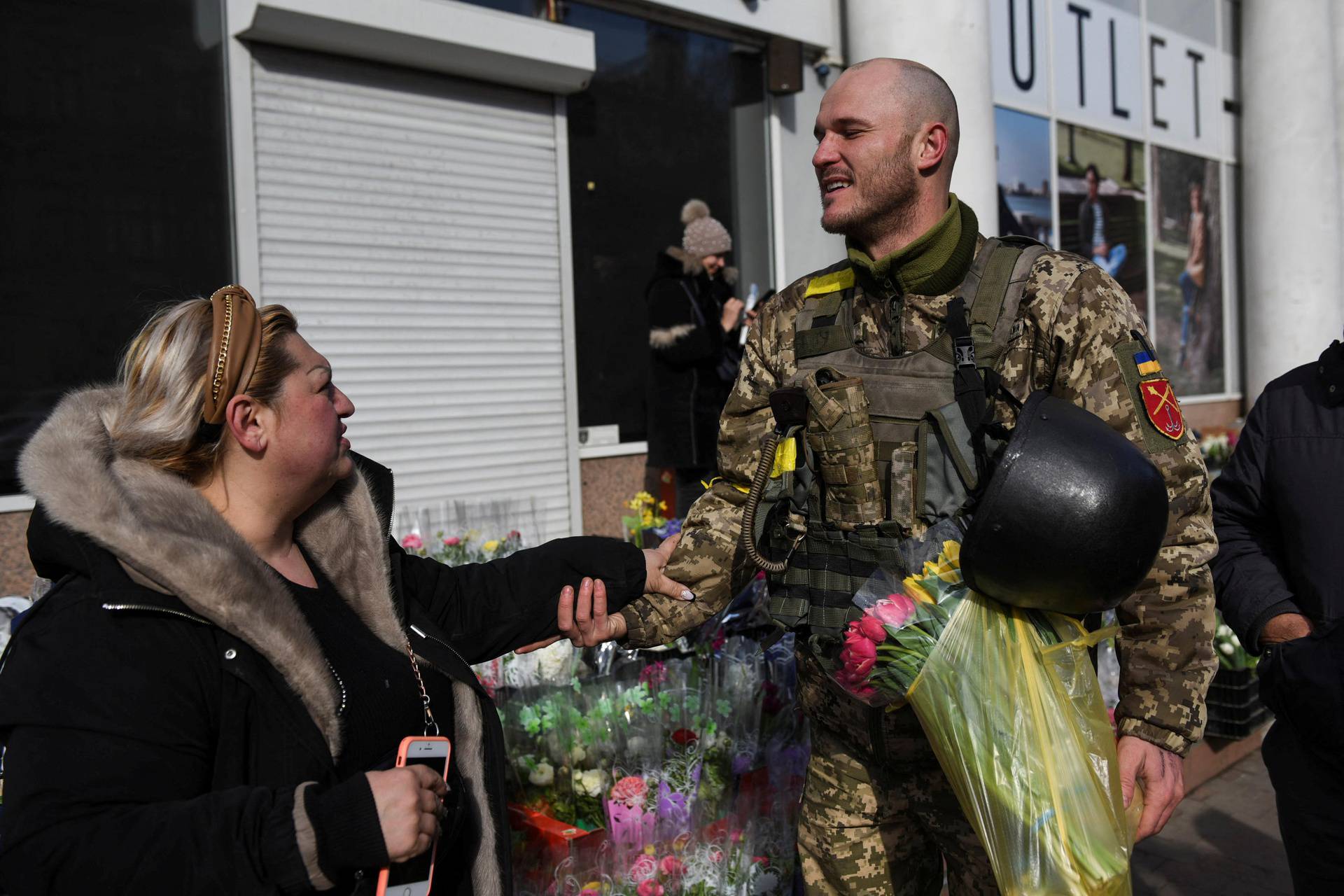 Ukrainian soldier Dmitriy, 32, is greeted by a woman after buying flowers at a street market, amid Russia's invasion of Ukraine, in Odessa