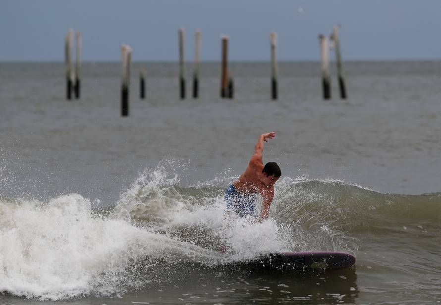 A surfer hits the waves with a backdrop of the Springmaid Pier that was damaged in 2016 by Hurricane Matthew ahead of the arrival of Hurricane Florence in Myrtle Beach