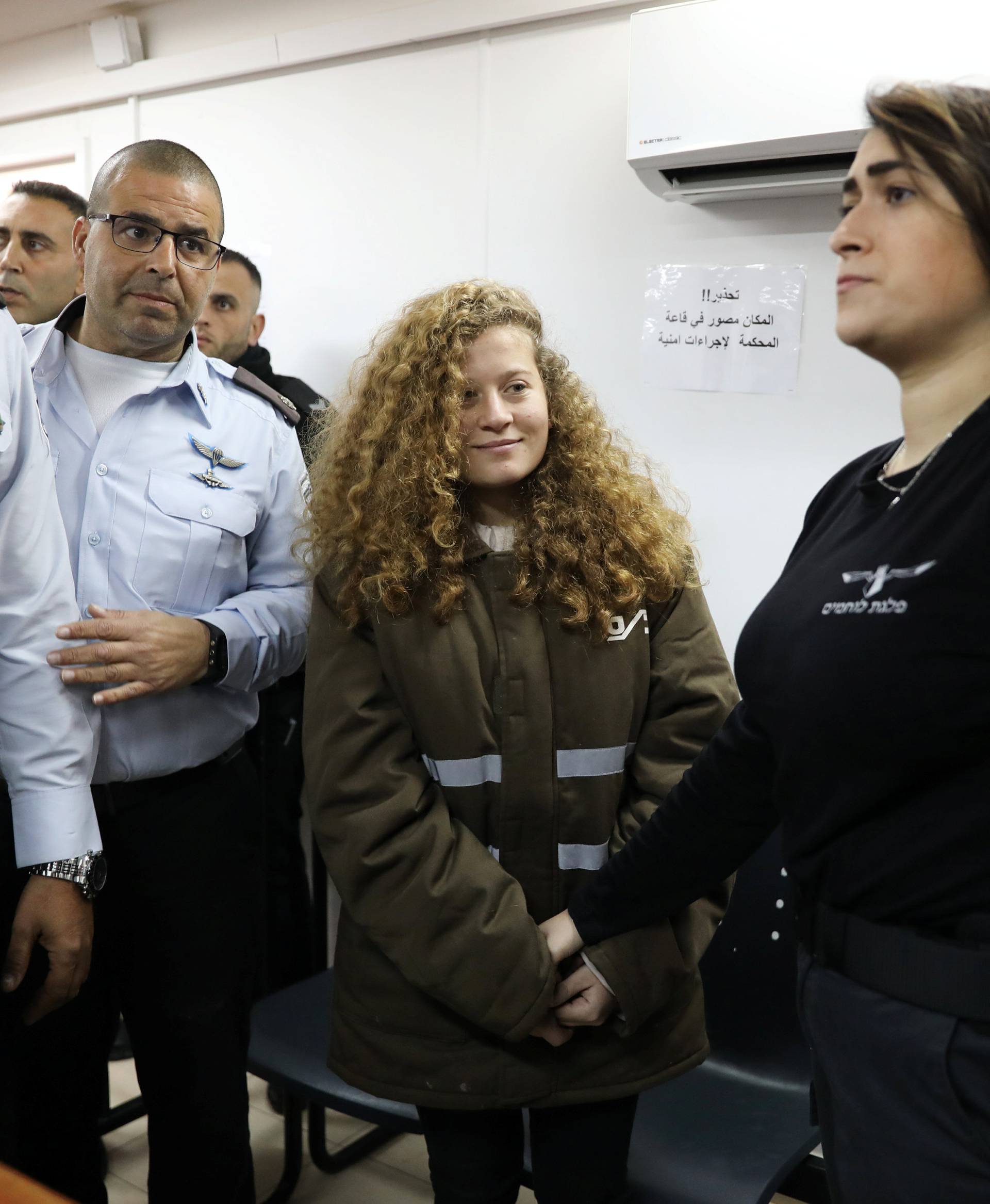 Palestinian teen Ahed Tamimi enters a military courtroom escorted by Israeli security personnel at Ofer Prison, near the West Bank city of Ramallah