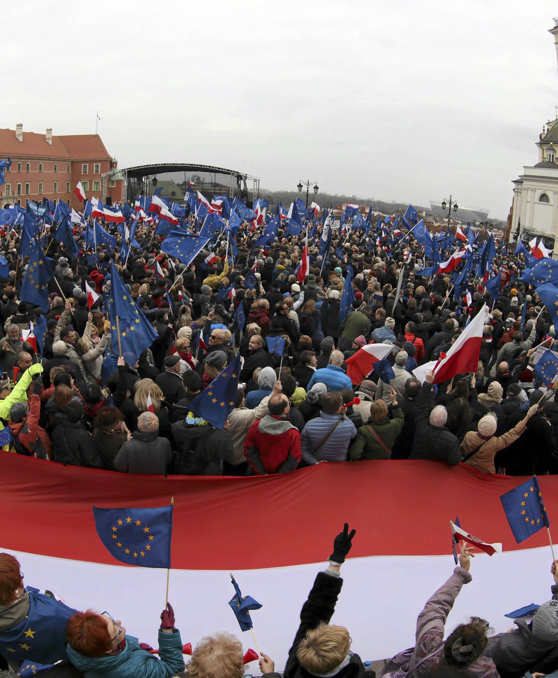 People hold giant Polish flag and EU flags as they attend a march called 'I love Europe' to celebrate the 60th anniversary of the Treaty of Rome in Warsaw