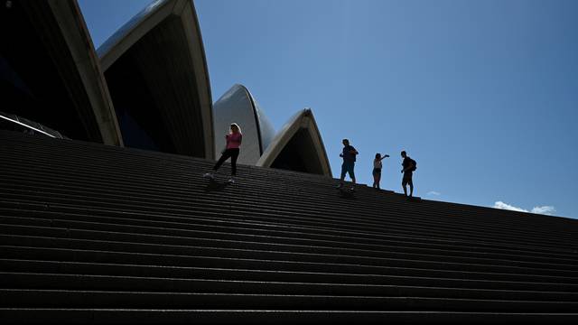 FILE PHOTO: A handful of tourists stand atop the mostly deserted steps of the Sydney Opera House in Sydney