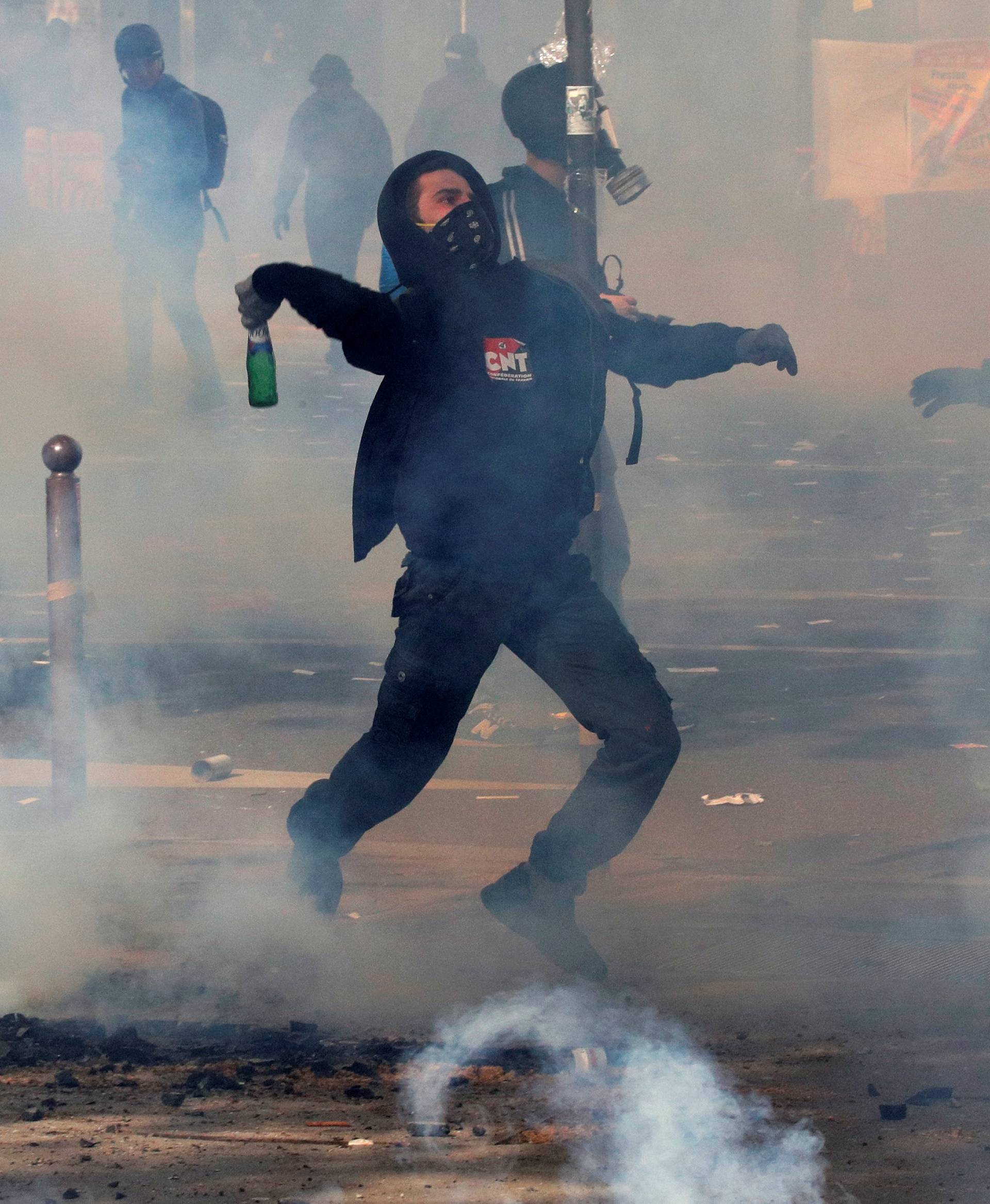 A masked protester throws a bottle during clashes with French CRS riot police at the May Day labour union rally in Paris