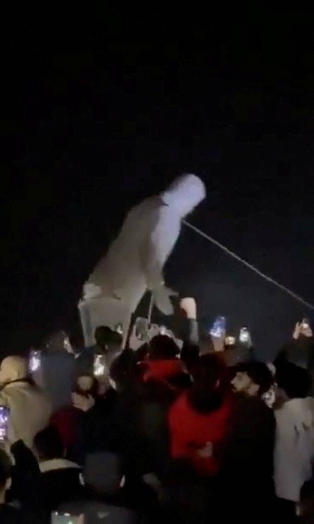 People cheer as the statue of former President of Syria Hafez al-Assad is toppled in Homs