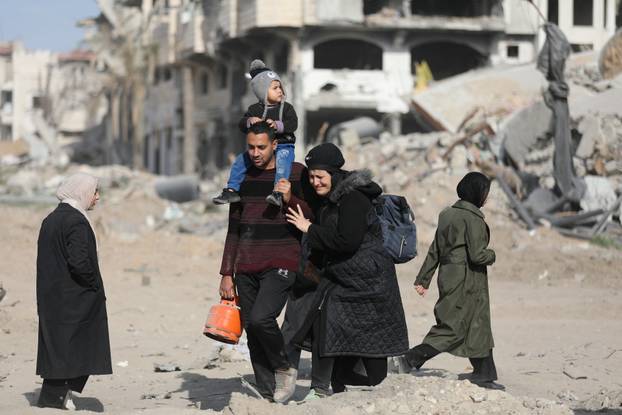 Displaced Palestinians walk past the rubble as they attempt to return to their homes, in the northern Gaza Strip