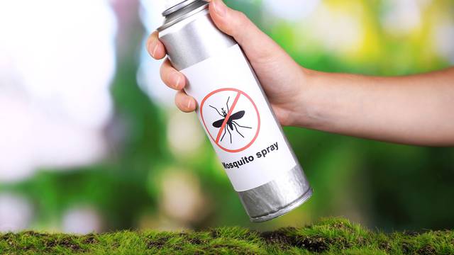 Hand holding mosquito spray on nature background