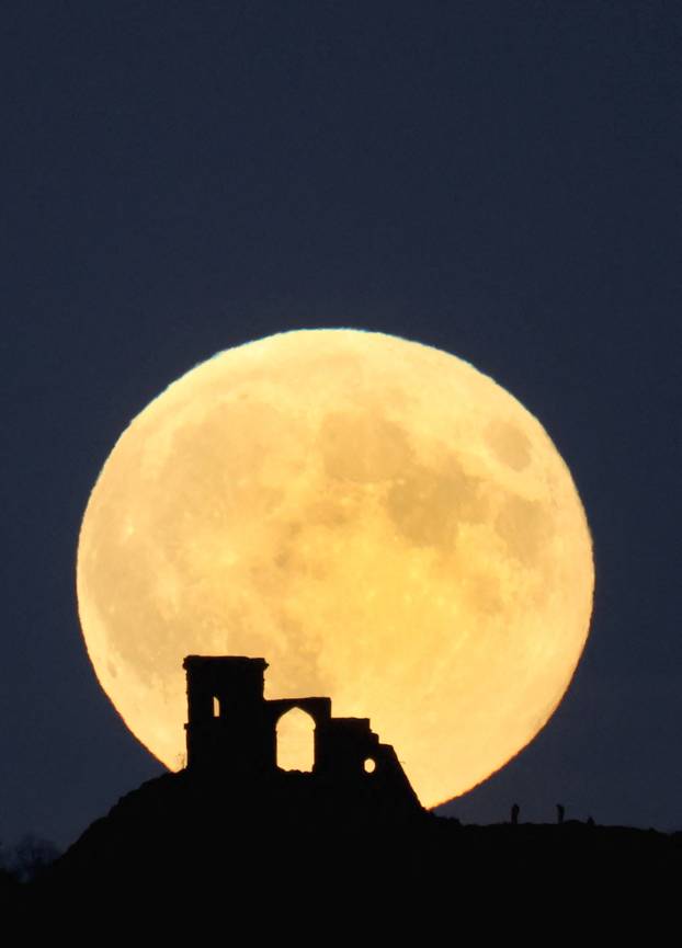 People watch as the Supermoon, known as the Hunter’s moon rises over Mow Cop castle in Mow Cop, Britain